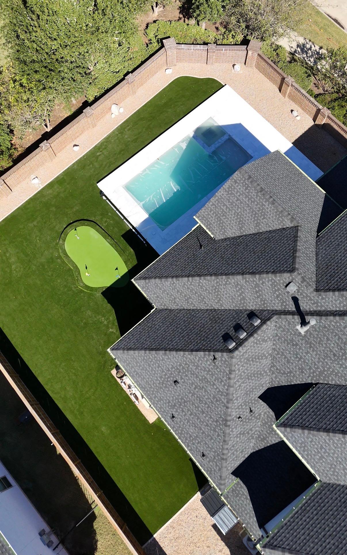 Aerial view of a luxury Houston backyard with a putting green, pool, and artificial turf
